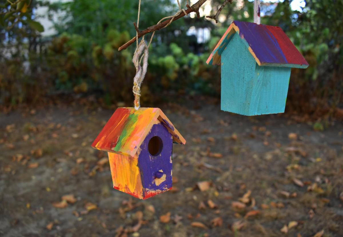 Wooden hand-painted birdhouses hanging in a tree.